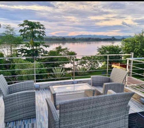 a balcony with chairs and a table and a view of a river at Chiang Khan Riverside Bungalows in Chiang Khan