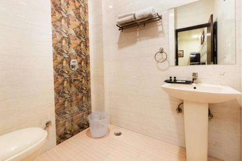 a bathroom with a sink and a toilet and a mirror at The Alpino Hotel in New Delhi