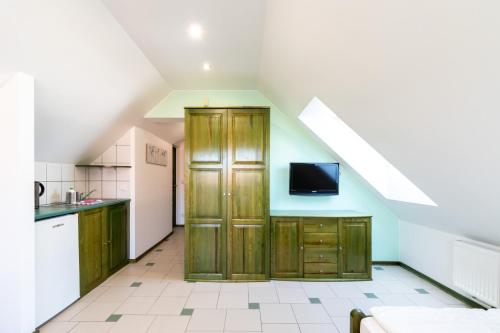 a kitchen with wooden cabinets and a tv on the wall at Villa & Domek Maja in Sarbinowo