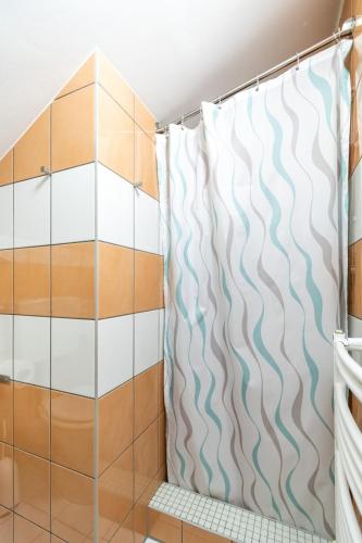 a shower curtain in a bathroom with wood and tile at Villa & Domek Maja in Sarbinowo
