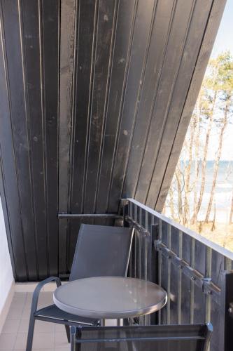 a table and a chair on a balcony at Villa & Domek Maja in Sarbinowo