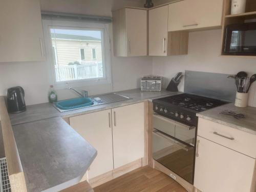 a kitchen with white cabinets and a stove top oven at 185 Holiday Resort Unity in Berrow
