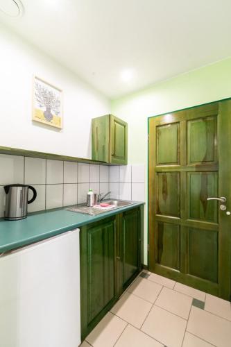 a kitchen with green cabinets and a door at Villa & Domek Maja in Sarbinowo