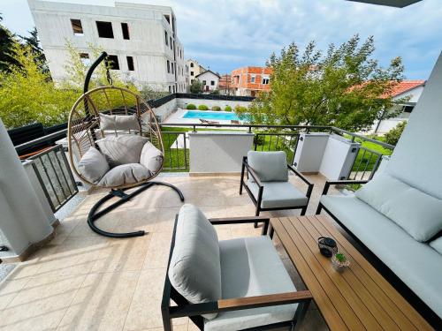 un balcón con una silla de mimbre y un columpio en Apartments Angelo en Bibinje