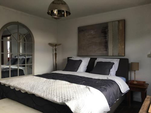 een slaapkamer met een groot bed met zwart-witte lakens bij Maison et son jardin situés dans le Condroz in Marchin