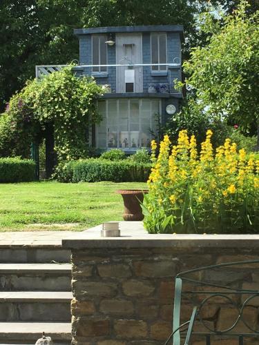 a house in the background with a garden with yellow flowers at Maison et son jardin situés dans le Condroz in Marchin