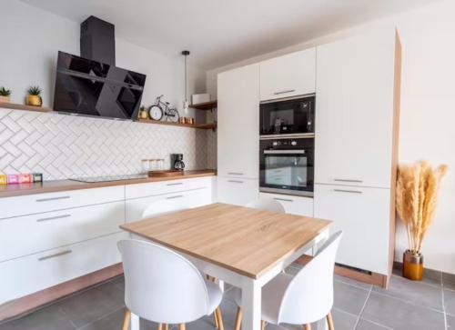 - une cuisine avec des placards blancs, une table en bois et des chaises blanches dans l'établissement Superb Apartment - Downtown Aix-en-Provence, à Aix-en-Provence