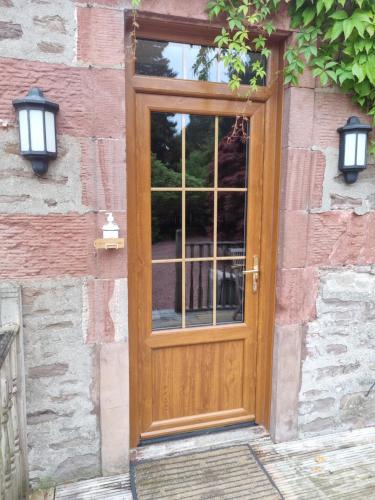 a wooden door on the side of a brick building at Auchendennan Farm Self Catering Cottages in Balloch