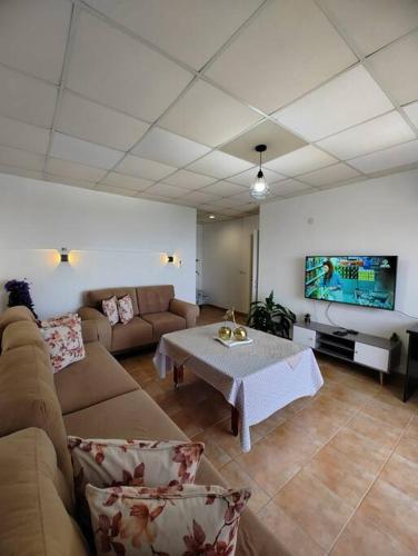 sala de estar con sofá, mesa y TV en Large Vacation Apartment With A Stunning View In Isfiya, Mount Carmel - דירת נופש עם נוף מדהים בעספיא, en ‘Isfiyā