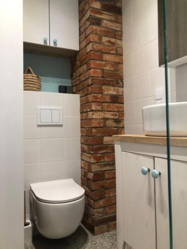 La salle de bains est pourvue de toilettes blanches et d'un mur en briques. dans l'établissement Niebieski klimat apartament 40m2, à Pruszcz Gdański