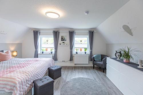 a bedroom with a bed and a desk and two windows at Jule Ahoi in Stedesand