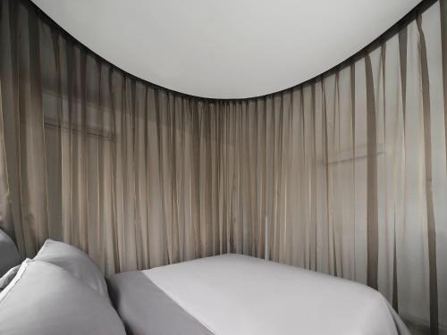 a bed in a room with curtains and a bedsheet at InJoy Snow Hotel in Ban Chuat Plai Mai