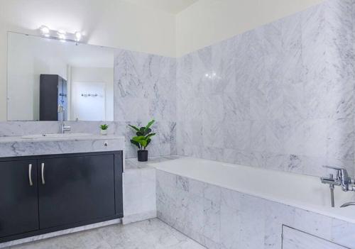 La salle de bains blanche est pourvue d'une grande baignoire et d'un lavabo. dans l'établissement T2 - Le Vadon, Bord de mer, à Saint-Raphaël