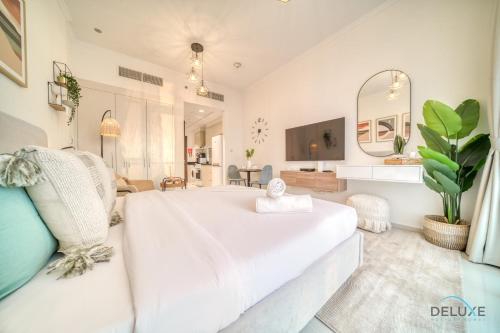 a white bedroom with a large white bed and a couch at Picturesque Studio at Carson A DAMAC Hills Dubailand by Deluxe Holiday Homes in Dubai