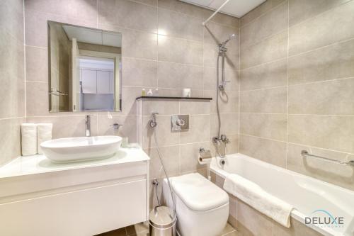 a bathroom with a sink and a tub and a toilet at Picturesque Studio at Carson A DAMAC Hills Dubailand by Deluxe Holiday Homes in Dubai