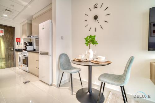 a kitchen with a table and chairs and a clock on the wall at Picturesque Studio at Carson A DAMAC Hills Dubailand by Deluxe Holiday Homes in Dubai