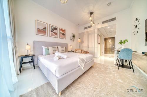 a bedroom with a large white bed and a desk at Picturesque Studio at Carson A DAMAC Hills Dubailand by Deluxe Holiday Homes in Dubai