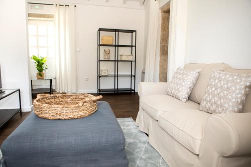 a living room with a white couch and a blue ottoman at Tio Zé - Casas de Selim in Arcos de Valdevez