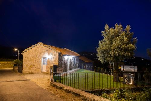 a stone building with a fence in front of it at night at Tio Zé - Casas de Selim in Arcos de Valdevez