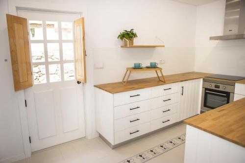 a kitchen with white cabinets and a window and a door at Mãe - Casas de Selim in Arcos de Valdevez