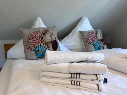 a pile of towels and pillows on a bed at Schmucke-Huus-Appartement-2 in Westerland