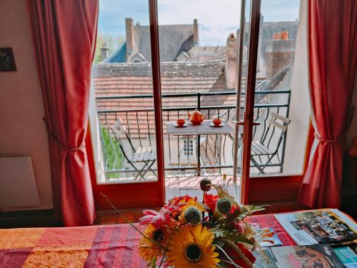 eine Vase mit Blumen auf einem Tisch vor einem Fenster in der Unterkunft Les Petites Forges in Auxonne