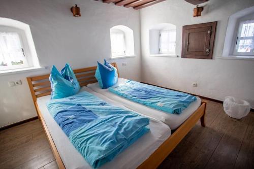 um quarto com uma cama com lençóis azuis e duas janelas em WIEDNERMICHL - Urlaub in den Weinbergen em Krottendorf bei Ligist