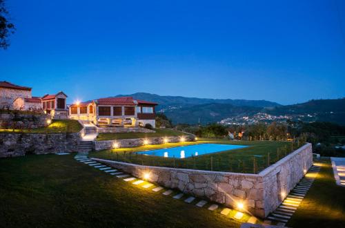 a villa with a swimming pool at night at Eira - Casas de Selim in Arcos de Valdevez
