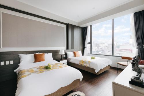 a hotel room with two beds and a large window at Ivy Hotel & Apartment - STAY 24h in Hanoi