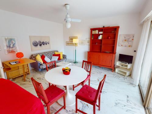 - un salon avec une table blanche et des chaises rouges dans l'établissement Grand studio avec terrasse, proche plages et centre-ville, Menton - FR-1-196-328, à Menton