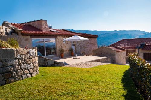 a stone house with an umbrella in a yard at Altiva - Casas de Selim in Arcos de Valdevez