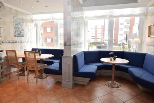 a restaurant with blue couches and tables and windows at Hotel Wiking Sylt in Westerland (Sylt)