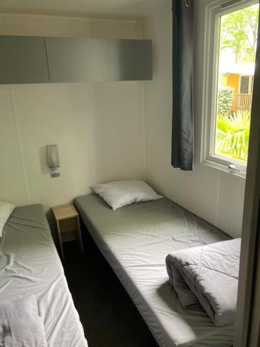 2 łóżka pojedyncze w pokoju z oknem w obiekcie Camping 5* - Biscarosse Lac - MobilHome 2 chambres - 4 personnes w mieście Biscarrosse