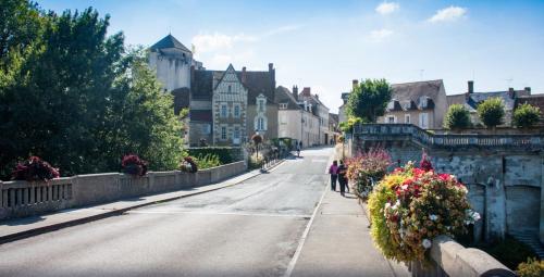 Une femme marchant dans une rue avec des fleurs sur un pont dans l'établissement Aux plumes, à La Roche-Posay