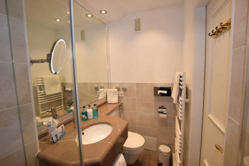 a bathroom with a sink and a toilet and a mirror at Hotel Wiking Sylt in Westerland (Sylt)