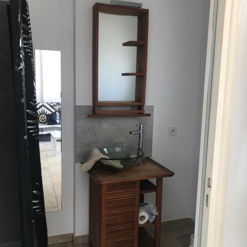 La salle de bains est pourvue d'un lavabo et d'un miroir sur une table. dans l'établissement Appartement proche des plages, à Porto-Vecchio