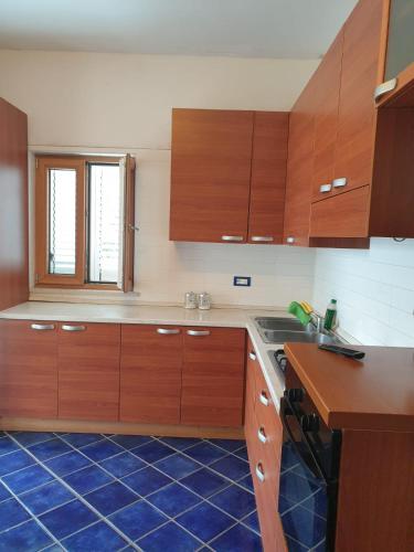 a kitchen with wooden cabinets and a blue tile floor at Hotel Mareluna Ischia in Ischia