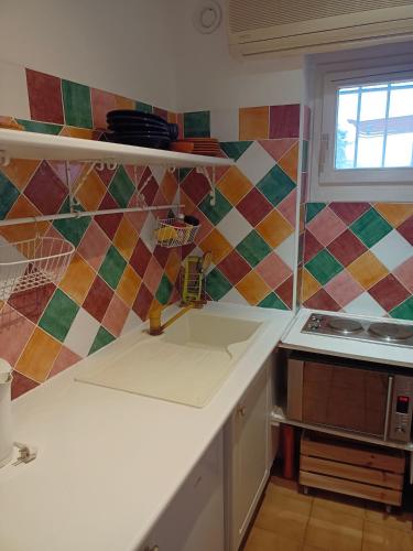 Il comprend une cuisine avec un évier et un mur en carrelage coloré. dans l'établissement Parc des Salins, à Hyères