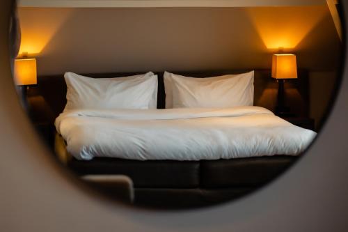 a bedroom with a bed with white sheets and pillows at Villa de Duinen - Adults Only in Noordwijk aan Zee