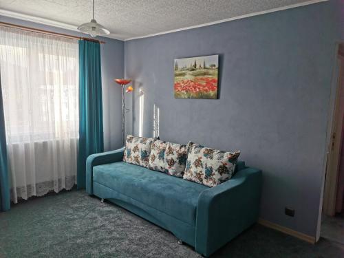 ein blaues Sofa im Wohnzimmer mit Fenster in der Unterkunft Apartament Ramona in Zărneşti