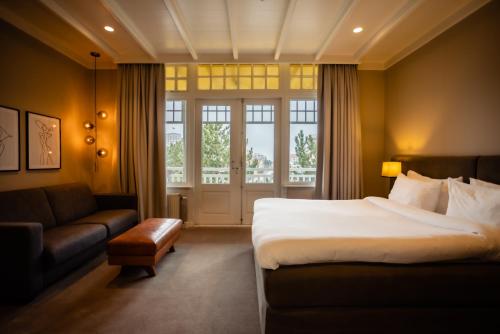 una camera d'albergo con letto e divano di Villa de Duinen - Adults Only a Noordwijk aan Zee