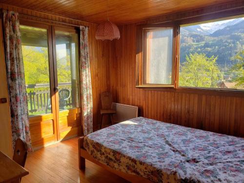 una camera da letto con un letto e una grande finestra di Chalet authentique à Samoëns : spacieux, 4 chambres, terrasse, garage - FR-1-629-103 a Samoëns