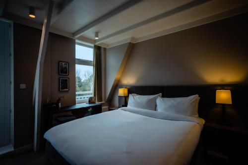 a large white bed in a room with a window at Villa de Duinen - Adults Only in Noordwijk aan Zee