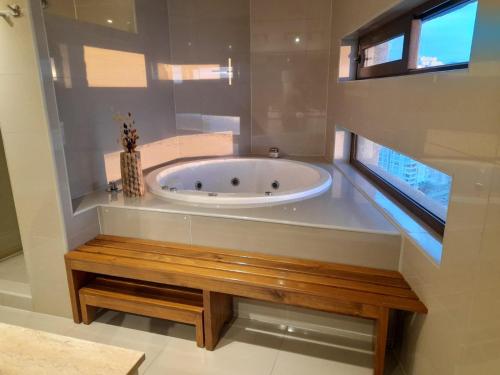 a bathroom with a tub with a wooden bench at Espectacular departamento de Lujo, al frente del mar in Coquimbo