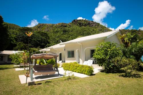 a white house with a mountain in the background at HideAway in Anse Possession
