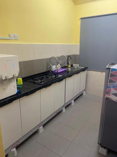 cocina con fogones y encimera blanca en Triple H Minionstay Kuala Terengganu, en Kuala Terengganu