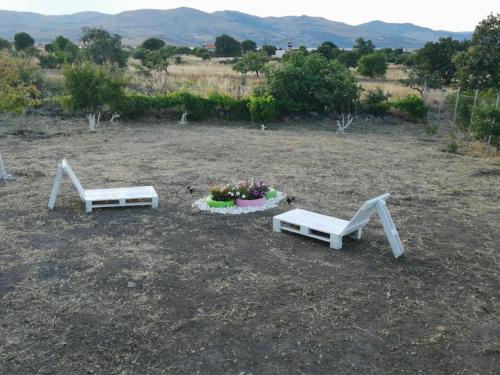 two white benches sitting in a dirt field at Ήσυχη μονοκατοικία κοντά στη θάλασσα!!! in Polichnítos