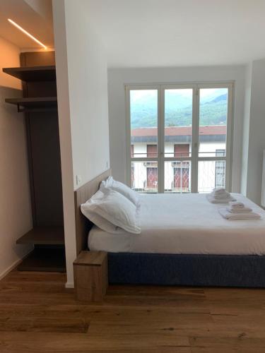 a bedroom with a bed and a large window at Hotel Corte Santa Libera in San Fedele Intelvi