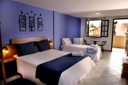 a bedroom with two beds and a blue wall at Pousada Flor de Penedo in Penedo