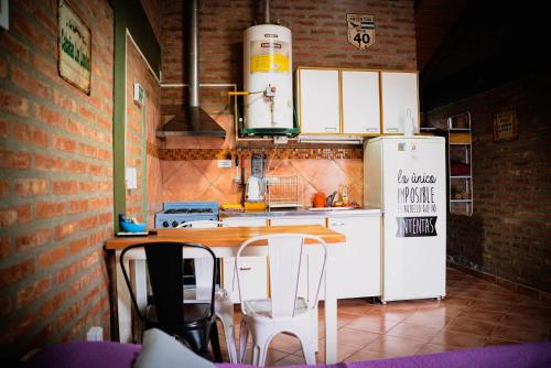cocina con nevera blanca, mesa y sillas en Cabañas Los Lúpulos en El Bolsón
